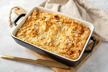 Pudding or oatmeal pie in a baking dish on a light gray culinary background. Casserole of cereals with nuts on the kitchen table closeup. Healthy and nutritious breakfast