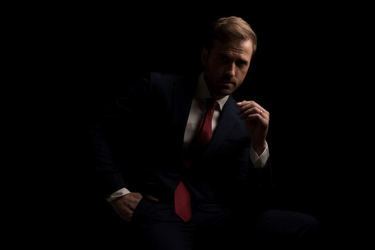 sexy seated businessman posing in the dark