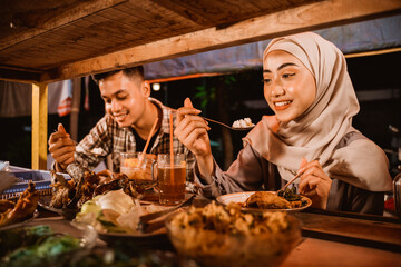 Fototapeta na wymiar muslim couple enjoy having iftar dinner at traditional food stall