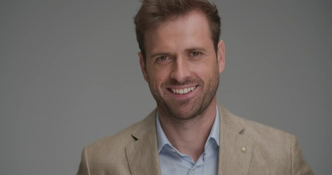 young businessman smiling at the camera and fixing his collar on gray background