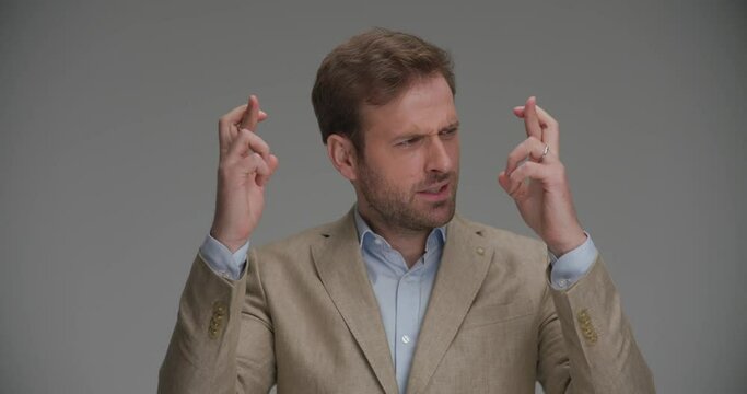 sexy businessman can't figure out what's wrong with his crossed fingers