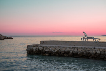 Deck chair at jetty in the evening light, Croatian coast of the island Pag
