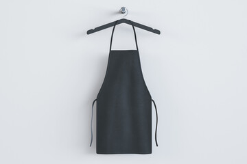 Empty black kitchen apron on hangers. Light background. Chef and cooking concept. Mock up place. 3D Rendering.