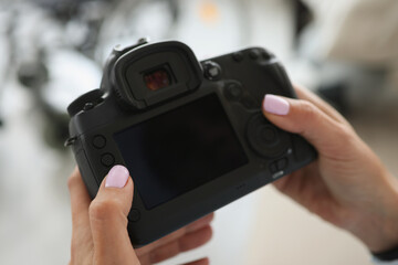 Female hands are holding a black modern camera