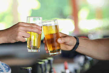 Male hands with glasses of beer clink glasses