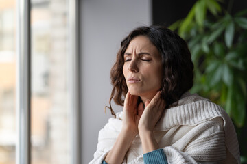 Frustrated woman touch neck check glands during cold, fever and seasonal influenza. Girl suffer from painful throat, ache, swallowing difficulties and loss of voice from angina or coronavirus illness