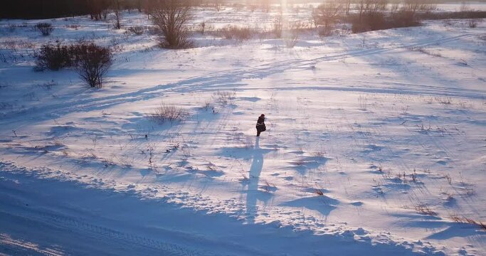 A man in a snake jacket walks through the deep snow in the frost. Evening, sunny. Side view. Snow virgin. Silhouette.