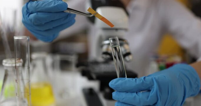 Scientist chemist checking acidity of liquid in test tube using litmus paper closeup 4k movie