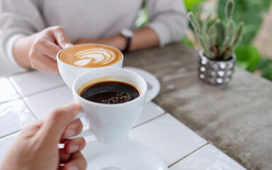 Closeup image of a couple people clinking coffee cups together in cafe
