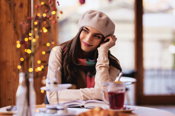 Beautiful young woman looking out the window and daydreaming while sitting at the coffee shop