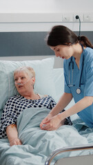 Obraz premium Doctor and nurse doing consultation with retired patient in hospital ward. Medical team examining diagnosis and treatment progress for ill woman with oximeter and nasal oxygen tube