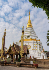 Naklejka premium Landscape view of ancient octagonal stupa or chedi with wooden pavilion and traditional Lanna style banners in foreground at ancient Wat Chiang Yuen buddhist temple, Chiang Mai, Thailand