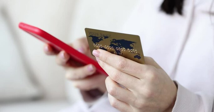 Woman holds credit card and uses mobile phone