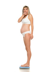 Obraz premium Young shocked pregnant woman standing on a scale