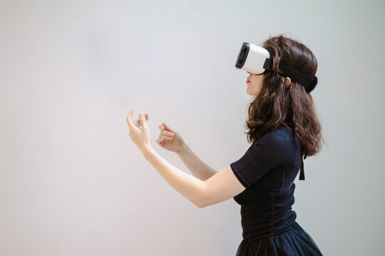 Young woman with VR glasses gesturing in studio