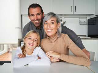 family consisting of father, mother and daughter talking by video call from the kitchen. family time