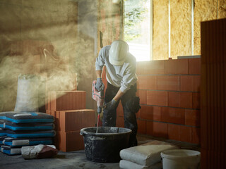 Bricklayer mixing cement in tub at construction site