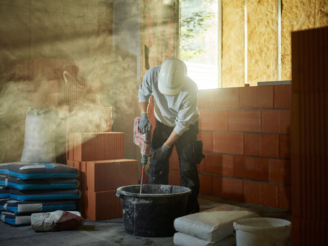 Bricklayer mixing cement in tub at construction site
