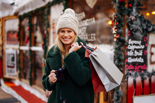 Smiling woman with shopping bags and wine mug at Christmas Market