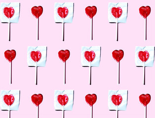 Pattern of heart shaped lollipops flat laid against pink background