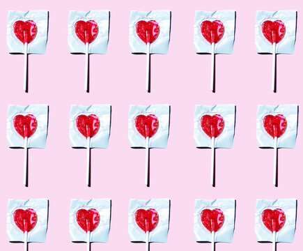 Pattern of heart shaped lollipops flat laid against pink background