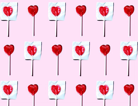 Pattern of heart shaped lollipops flat laid against pink background