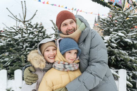 Smiling Father Embracing Children At Backyard In Winter