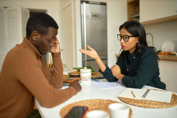 Two young business partners male and female of black ethnicity sitting at kitchen table, discussing...