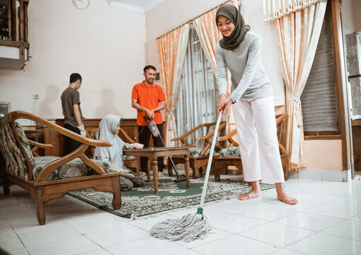 veiled mother mopping the floor while cleaning the house together