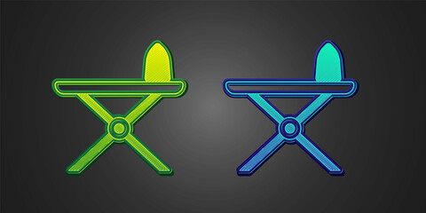 Green and blue Electric iron and ironing board icon isolated on black background. Steam iron. Vector