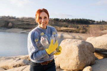 Smiling volunteer holding plastic bottles at beach