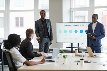 Portrait of young African-American woman speaking to colleague during business meeting in office