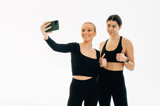Two young women taking selfies together at the gym