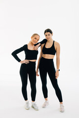 Portrait of two fit young women standing over white background