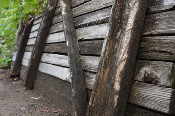 Wooden fence with a supporting frame. Old gray boards. Horizontal boards and slits. bars. Green plants in the background.