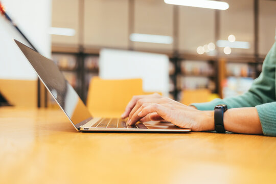 Businesswoman's hands typing on laptop at desk in office - Powered by Adobe