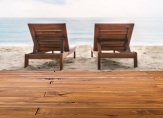Fototapeta na wymiar Beautiful brown plank wooden table or desk floor, little shiny surface, perspective view, the background of blurred sunbeds on the beach. Empty space for products to put on the table.