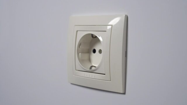 Person unplugs electrical plug from home electric socket. Saving expensive electricity and the energy crisis concept. Conceptual view