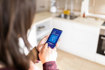 Woman adjusting brightness using smart home application on mobile phone at home