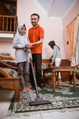 Father and daughter use vacuum to clean carpet