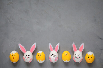 Easter eggs decorated as bunnies and chicks on the gray background. Copy space.