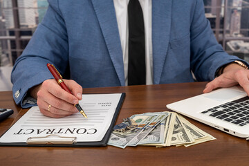 business man in a strict suit with dollars in his hands signs an important business contract.