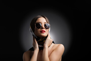 Close up photo of an attractive young woman with bare shoulders in sunglasses and beautiful shawl with make-up, retro music concept.