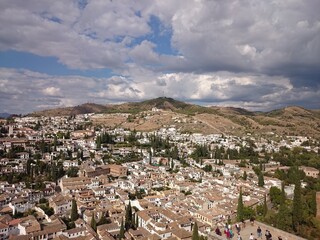 Fototapeta na wymiar Top view of Granada, sightseeing from alcazaba, ancient city of Spain. White houses with tiled roofs in a hot climate. Mobile photography, travel route