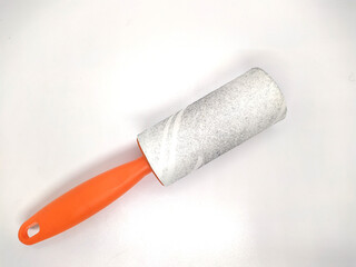 Orange roller for cleaning clothes on a white background.