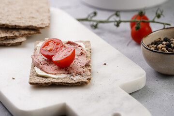 Healthy crunchy crisp bread sandwich with chicken pate, cream cheese and cherry tomatoes on marble board