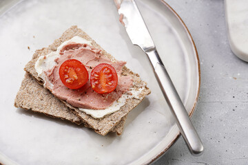 Healthy crunchy crisp bread sandwich with chicken pate, cream cheese and cherry tomatoes on round...