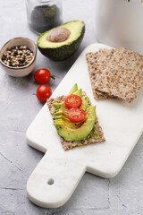Healthy crunchy crisp bread sandwich with avocado and cherry tomatoes on marble board