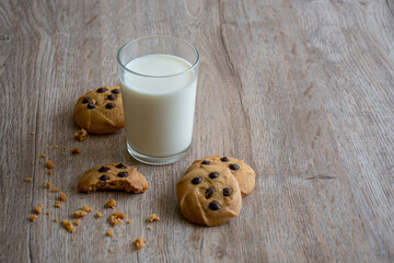 plate with chocolate chip cookies and a glass of milk on blurred background