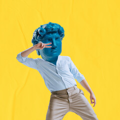 Young man headed by blue statue head dancing isolated on yellow background. Contemporary colorful...